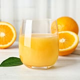 glass of orange juice with oranges in background