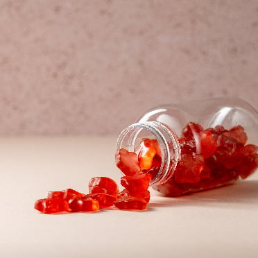 Red gummy supplements spilling out of container