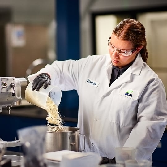 scientist pouring ingredents into a pot