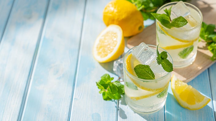 two lemon and mint drinks in a glass