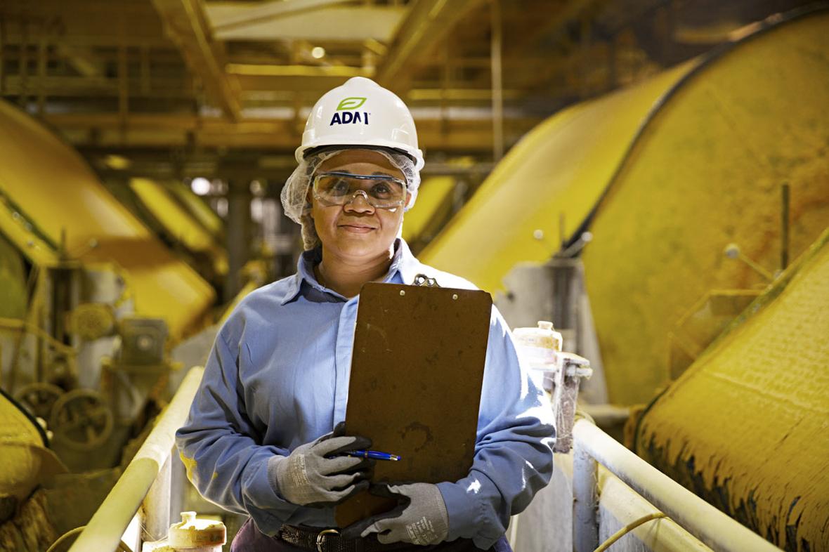 Woman in hard hat smiling in factory