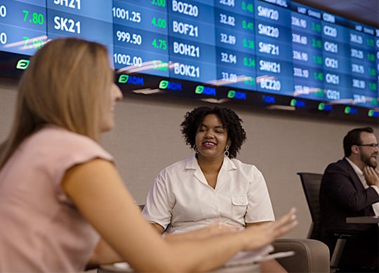 women talking in front of stock ticker symbol