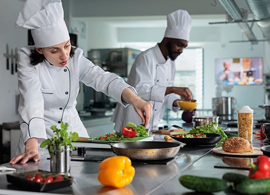 C50 female and male chefs developing dishes in restaurant kitchen