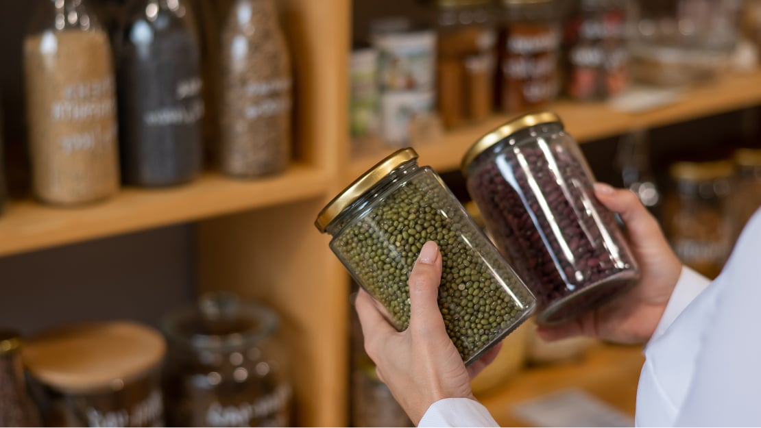 A person holding jars of beans