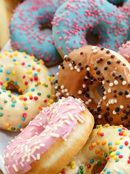 platter of multi-colored donuts with sprinkles