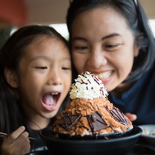 C12 Mother and child smiling enjoying chocolate and whipped cream dessert cake