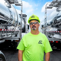 C58 Male ADM employee wearing hard hat near 2 tanker trucks